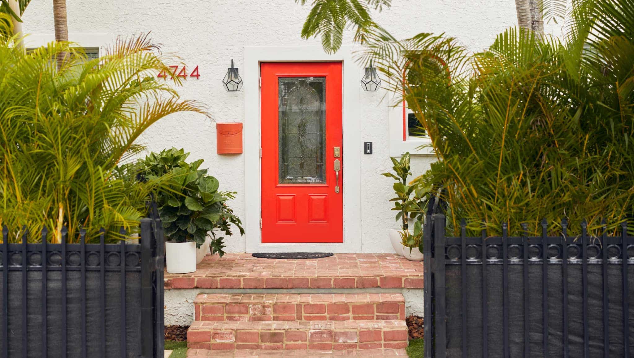 鲜红色的前门与浅色的房屋外观和黑色的前院栅栏形成对比