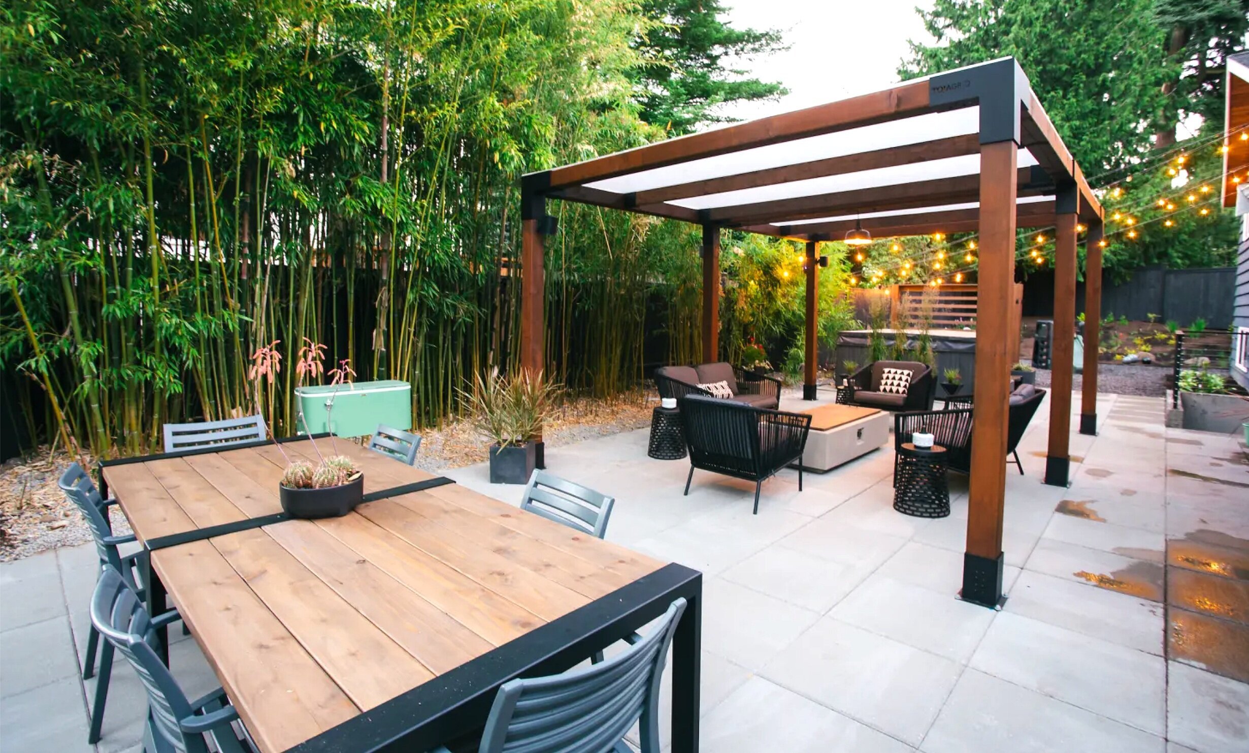 一个铺有栅栏和竹子的后院，用于隐私和凉棚，透明的屋顶遮阳火炭座位区
