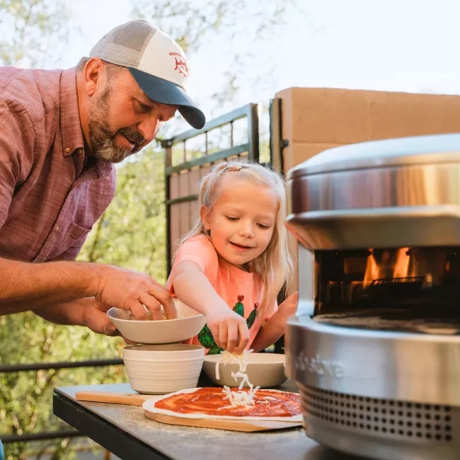 一个女儿和她的父亲聚集在一个派披萨烤箱从独奏炉