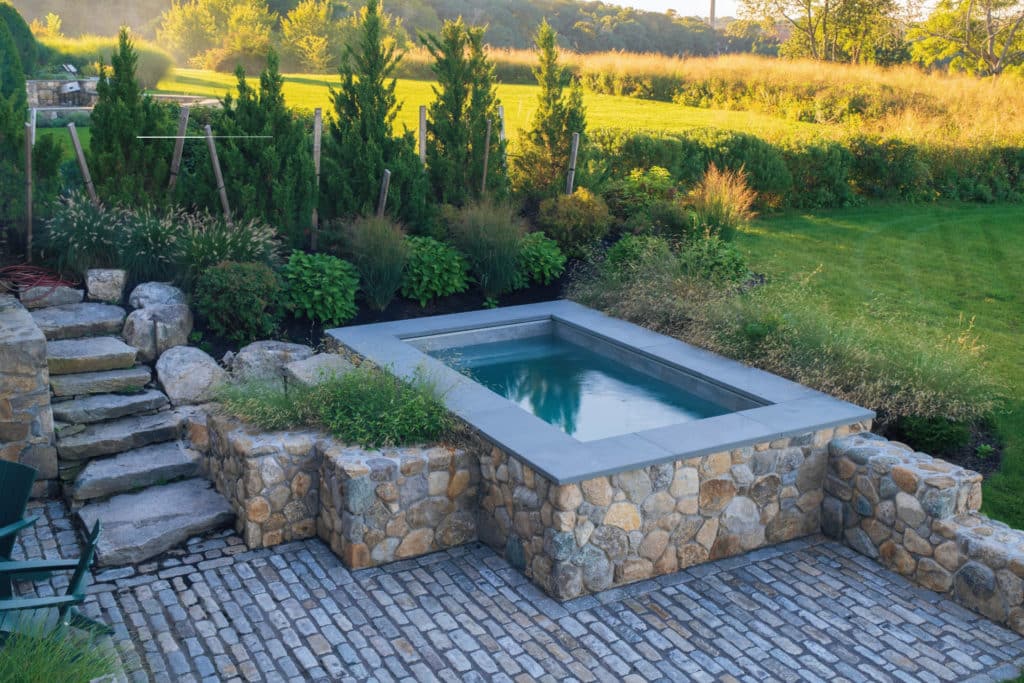 地面上的跳水池与质朴的石头完成和田园花园和草坪的背景。